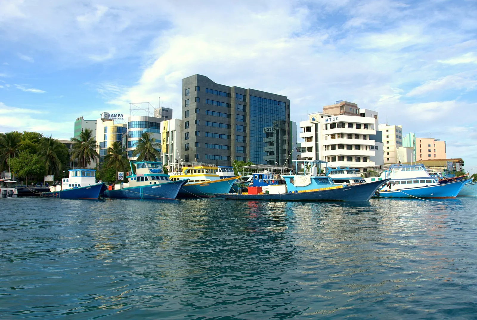 Maldives Monetary Authority headquarters and modern office buildings beside boats in Malé harbour